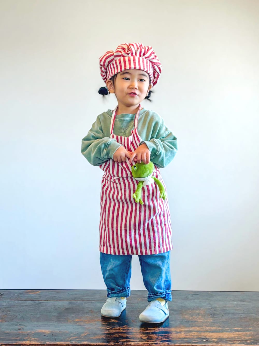 グリーン系のスウェット、ブルー系のデニムパンツ、ブルー系のサンダルを着用したキッズの秋コーディネートの2枚目の写真