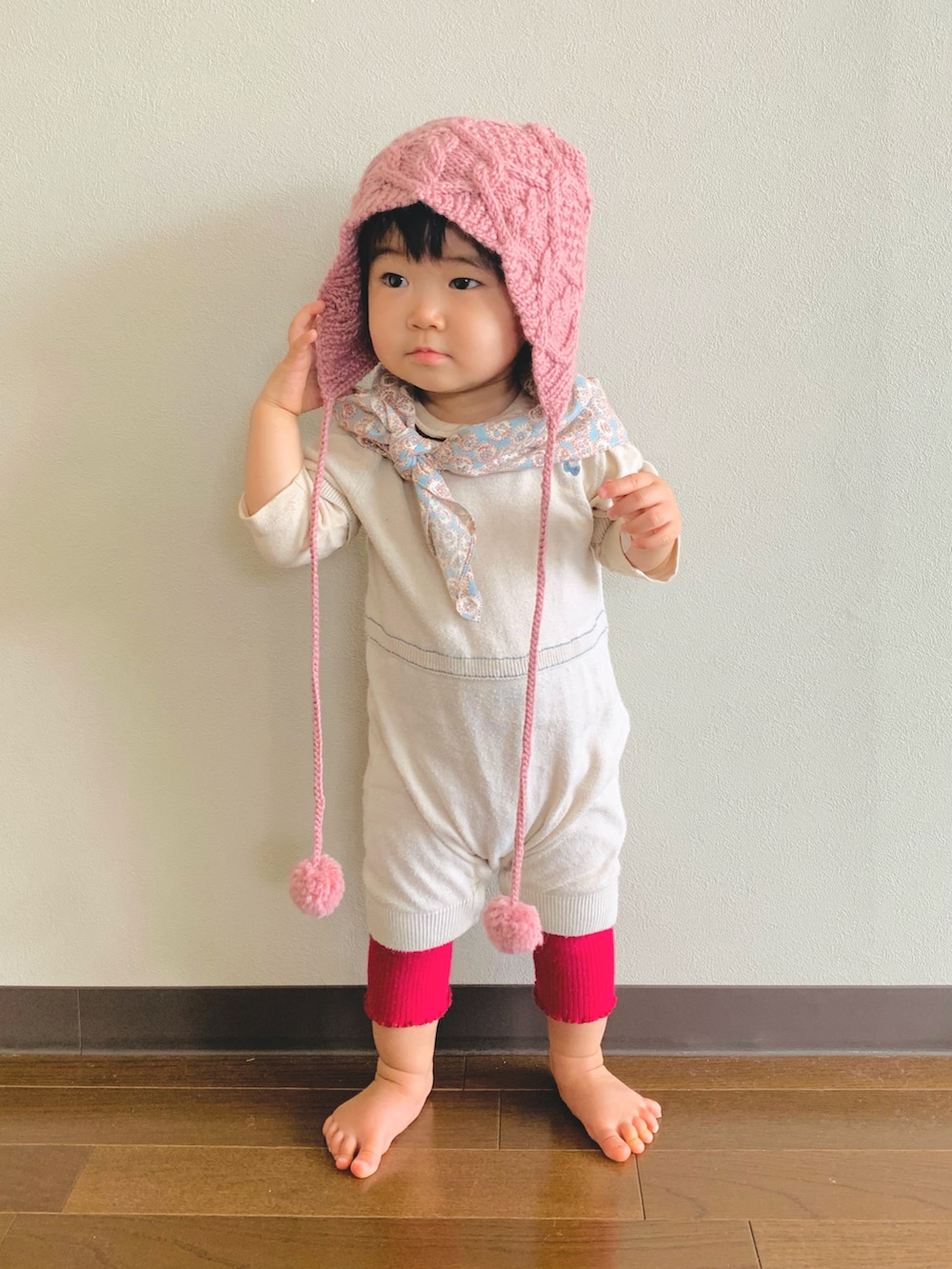 ベージュ系のロンパース、ピンク系のニットキャップ/ビーニー、ブルー系のハンカチ/ハンドタオルを着用したキッズの秋コーディネートの2枚目の写真