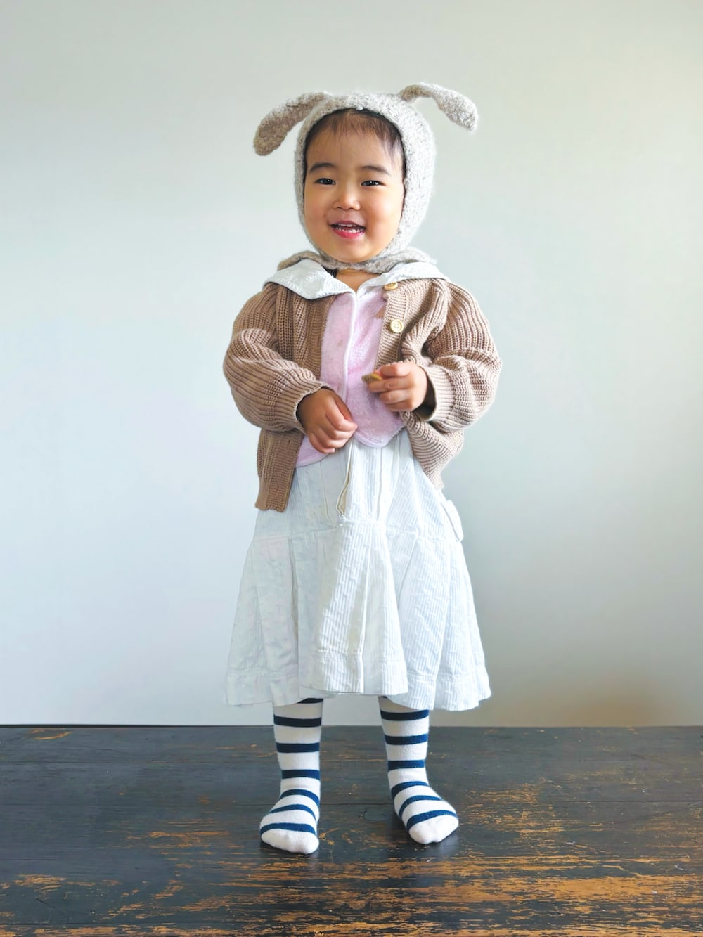 ホワイト系のワンピース、ピンク系のベスト、ブラウン系のセットアップを着用したキッズの秋コーディネートの2枚目の写真