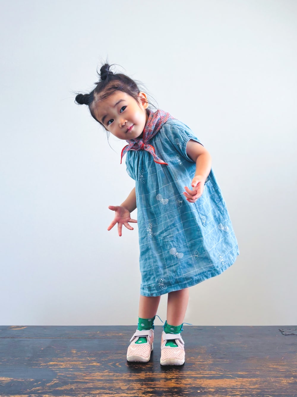 ピンク系のスニーカー、ブルー系のワンピース、オレンジ系のバンダナ/スカーフを着用したキッズの夏コーディネートの3枚目の写真