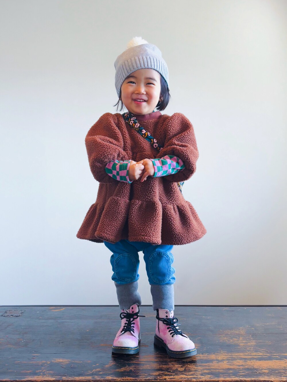 ピンク系のブーツ、ブルー系のデニムパンツ、ブラウン系のワンピースを着用したキッズの冬コーディネートの2枚目の写真
