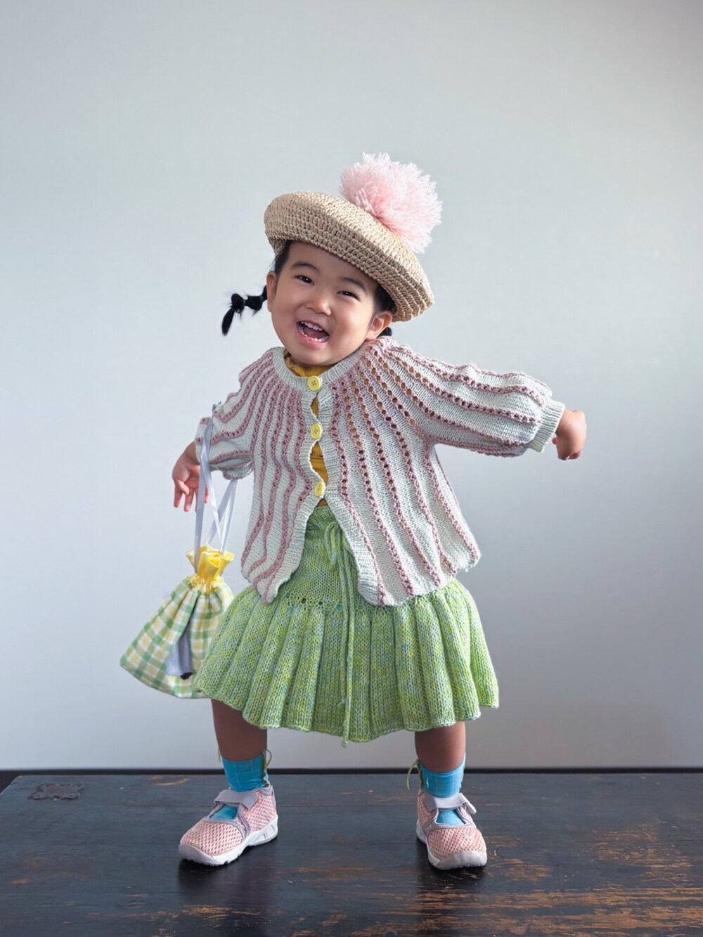 ピンク系のカーディガン/ボレロ、イエロー系のTシャツ/カットソー、グリーン系のスカートを着用したキッズの春コーディネートの3枚目の写真