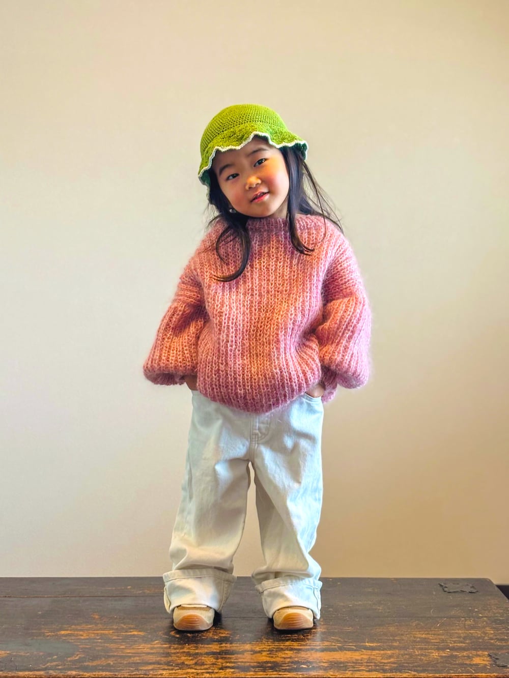 イエロー系のスニーカー、ピンク系のニット/セーター、ホワイト系のデニムパンツを着用したキッズの冬コーディネートの3枚目の写真