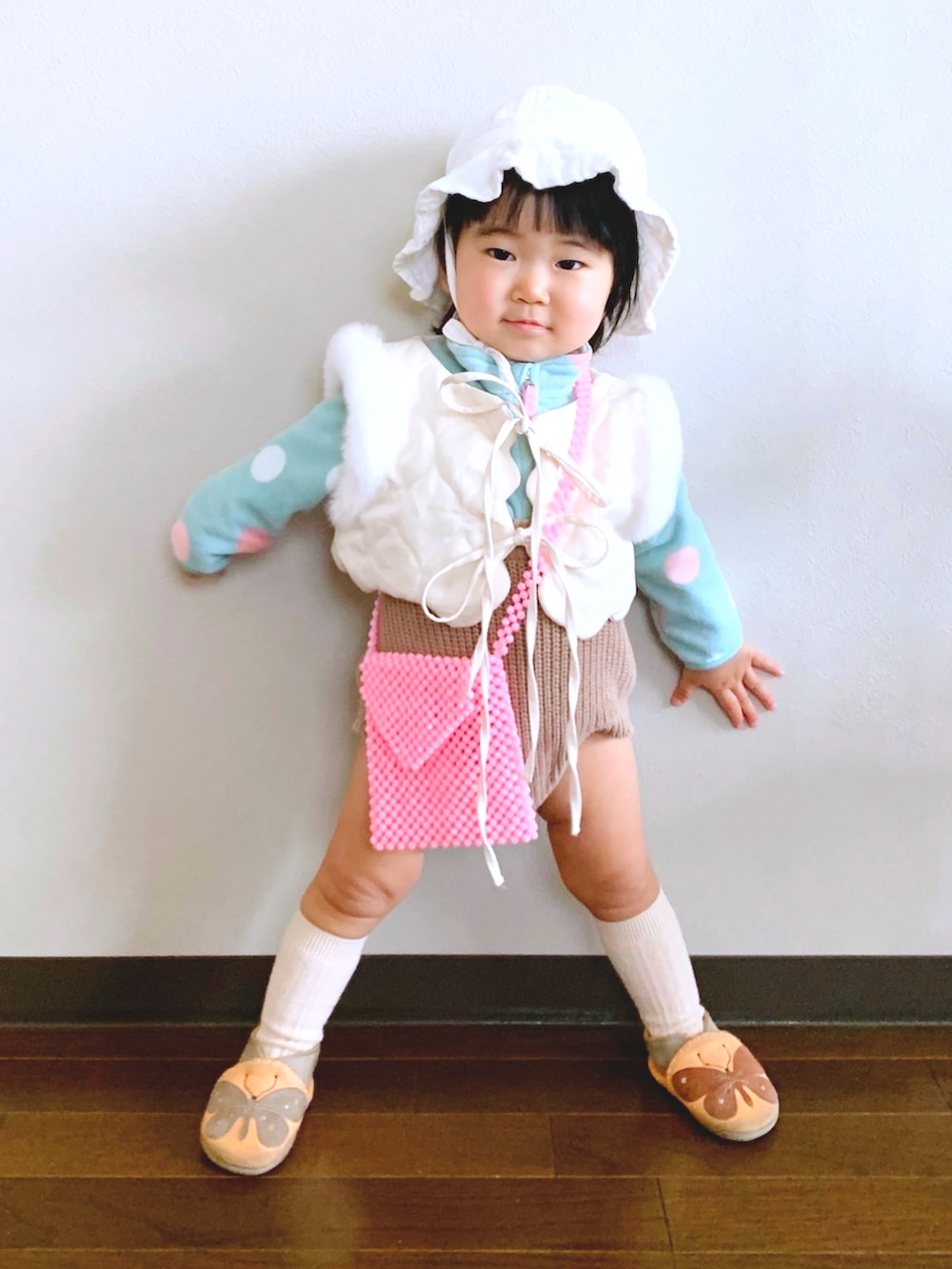 オレンジ系のスリッポン、ピンク系のショルダーバッグ、ブラウン系のセットアップを着用したキッズの冬コーディネートの2枚目の写真