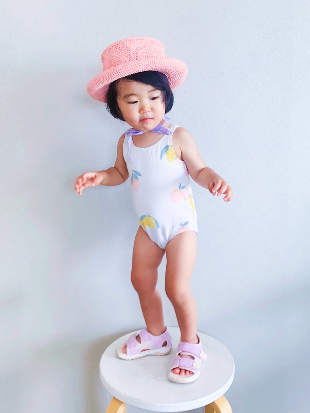 ピンク系のサンダル、ピンク系のハット、ベージュ系の水着を着用したキッズの夏コーディネートの2枚目の写真