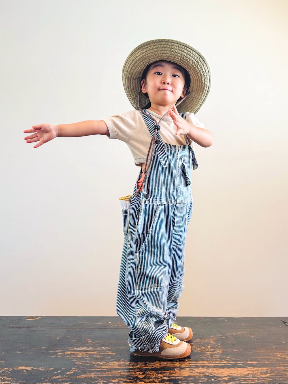 イエロー系のスニーカー、オレンジ系のその他パンツ、ベージュ系のTシャツ/カットソーを着用したキッズの秋コーディネートの2枚目の写真