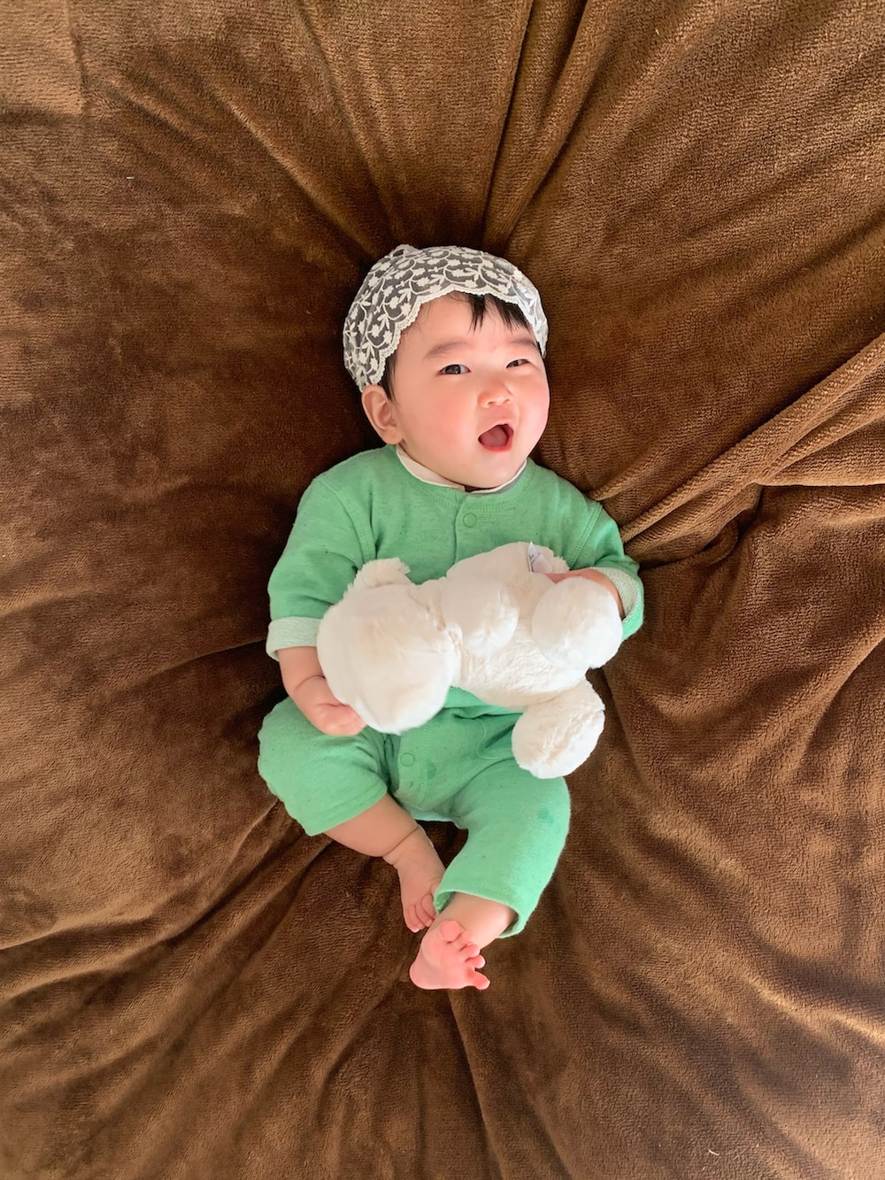 ホワイト系のおもちゃ、グリーン系のロンパース、ホワイト系のロンパースを着用したキッズの春コーディネートの2枚目の写真