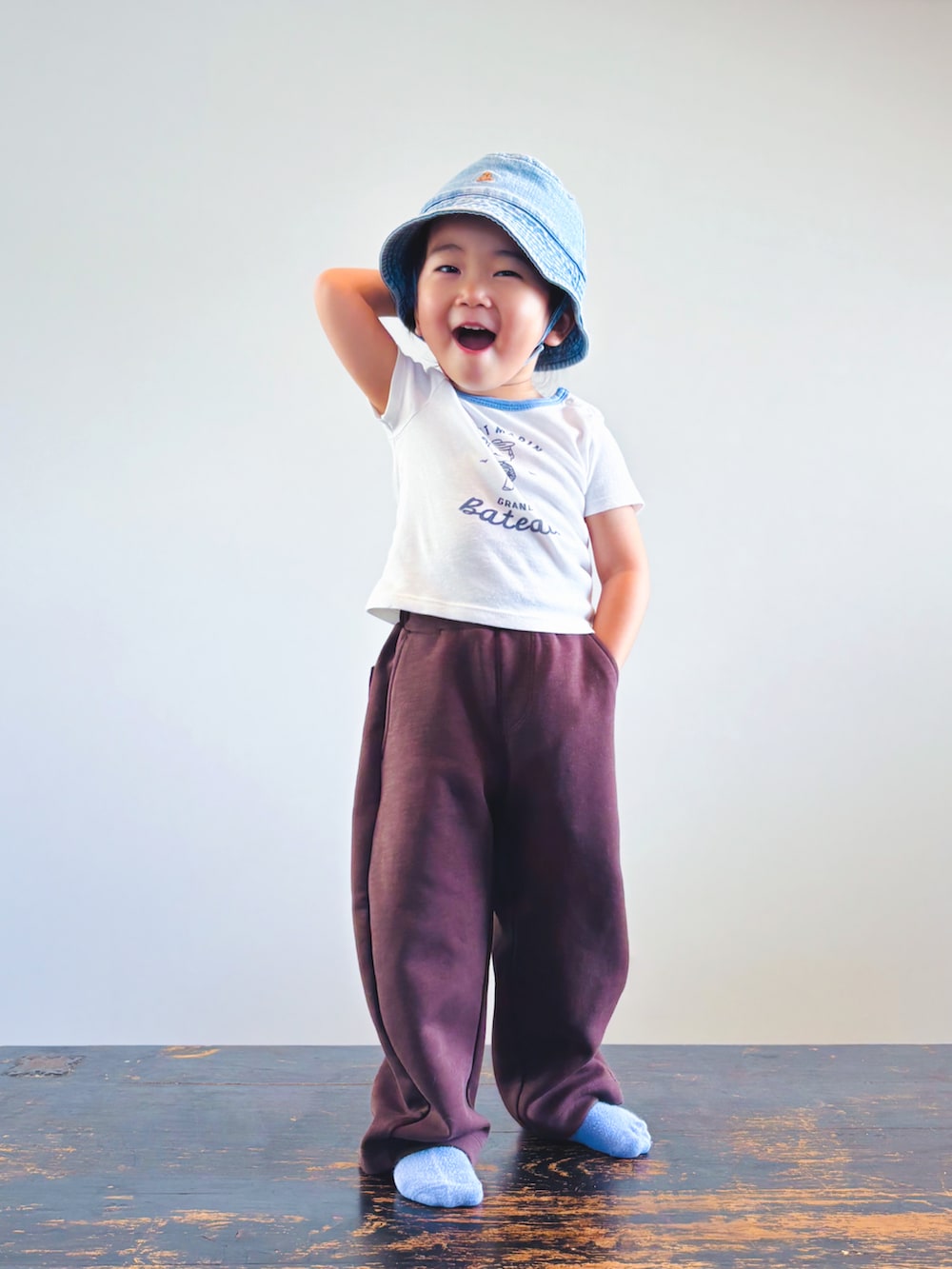 ホワイト系のTシャツ/カットソー、ブラウン系のスウェットパンツ、ブルー系のハットを着用したキッズの夏コーディネートの3枚目の写真