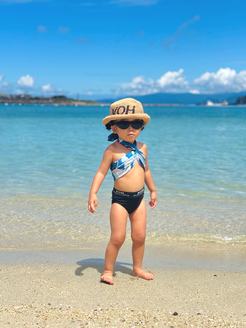 ブラック系のサングラス、ブルー系のバンダナ/スカーフ、ベージュ系のハットを着用したキッズの夏コーディネートの2枚目の写真