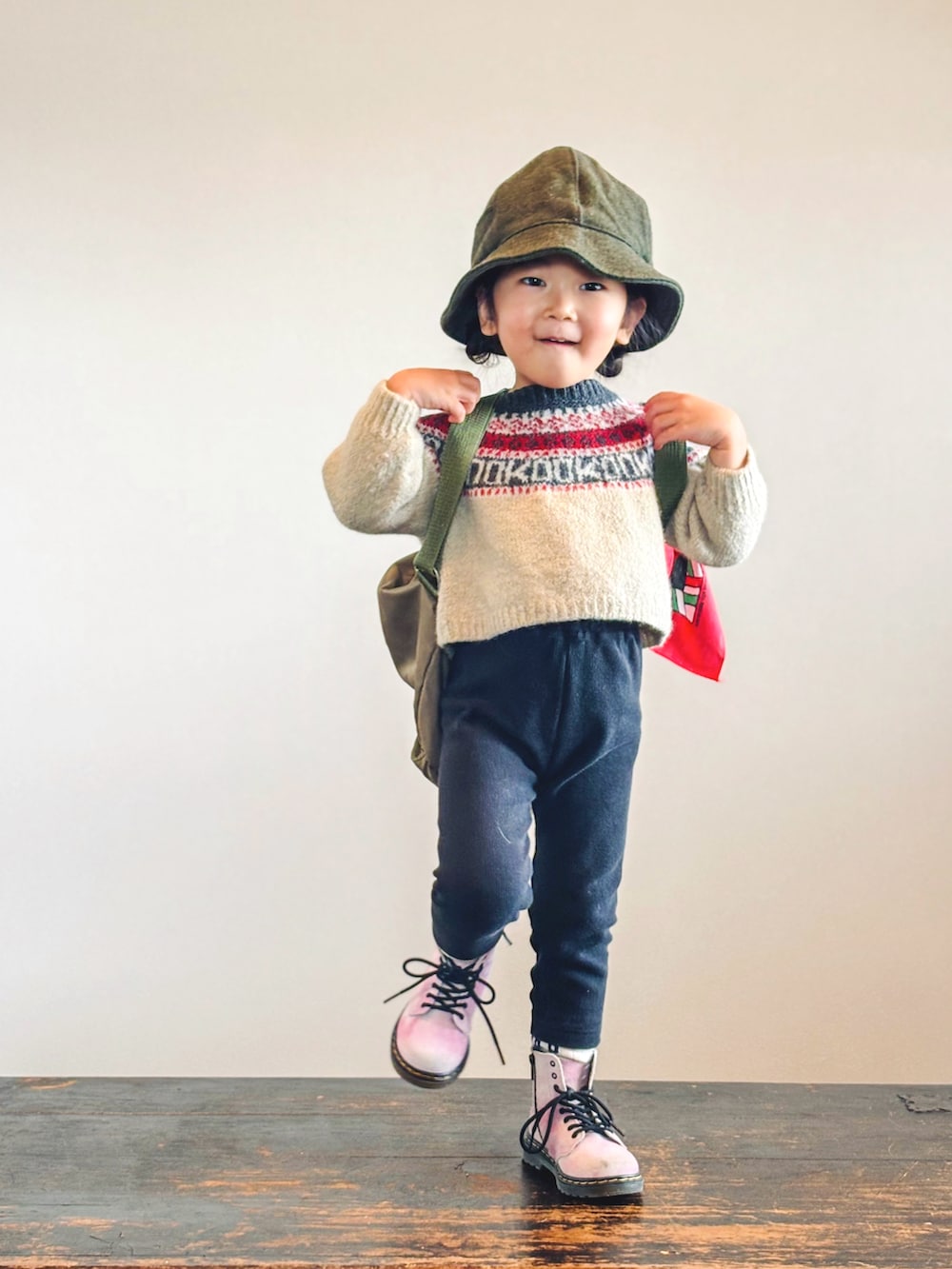 ベージュ系のニット/セーター、ブラック系のパンツ、グリーン系のバックパック/リュックを着用したキッズの秋コーディネートの2枚目の写真