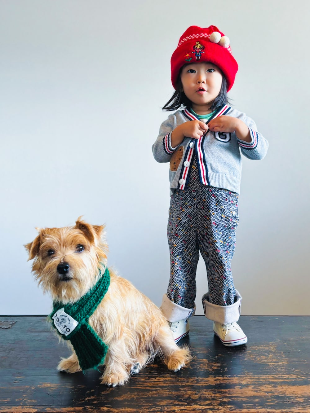 グレー系のカーディガン/ボレロ、その他のサロペット/オーバーオール、ホワイト系のスニーカーを着用したキッズの秋コーディネートの2枚目の写真