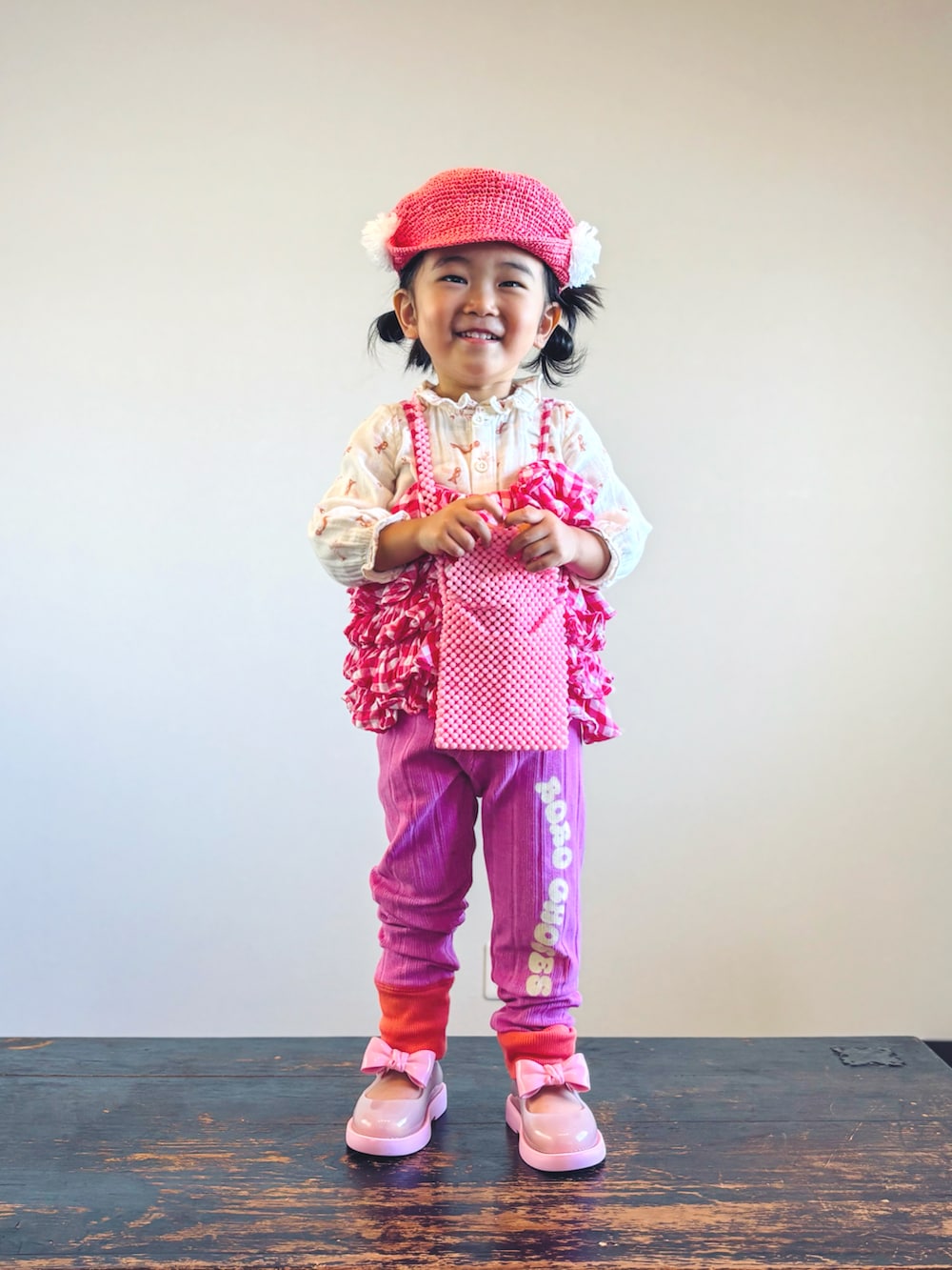 ピンク系のキャミソール、ベージュ系のシャツ/ブラウス、ピンク系のショルダーバッグを着用したキッズの秋コーディネートの3枚目の写真