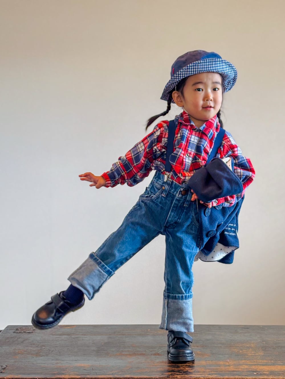 レッド系のシャツ/ブラウス、ブラック系のポンチョ、ブルー系のデニムパンツを着用したキッズの秋コーディネートの3枚目の写真