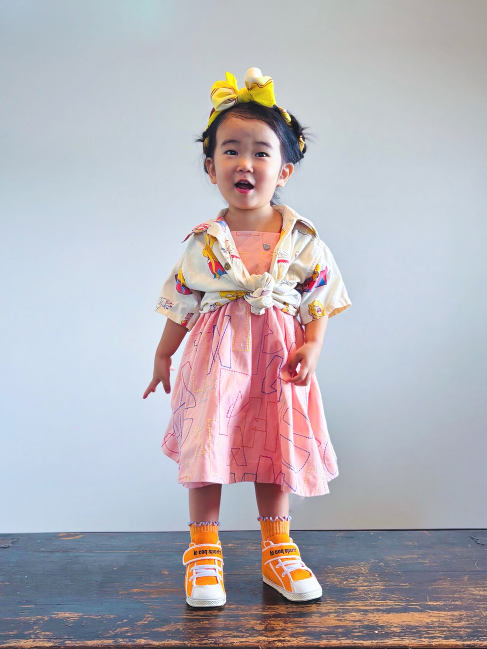 オレンジ系のスニーカー、オレンジ系のワンピース、ベージュ系のシャツ/ブラウスを着用したキッズの夏コーディネートの2枚目の写真
