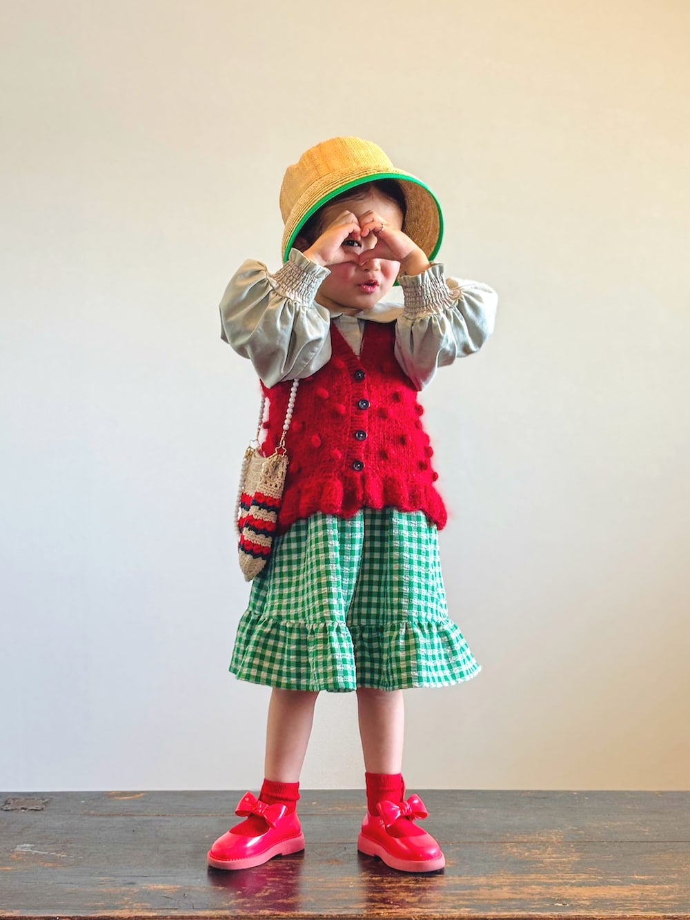 グリーン系のスカート、レッド系のベスト、グリーン系のシャツ/ブラウスを着用したキッズの春コーディネートの2枚目の写真