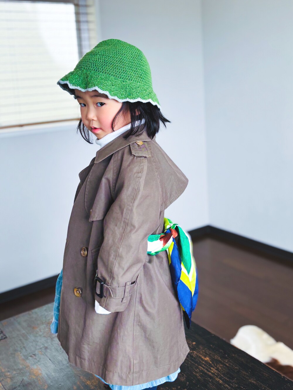 グリーン系のトレンチコート、ホワイト系のTシャツ/カットソー、ブルー系のワンピースを着用したキッズの春コーディネートの3枚目の写真