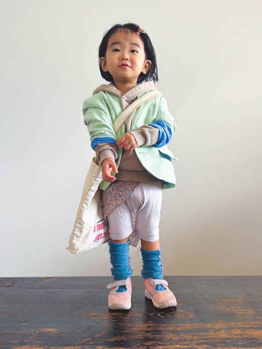ピンク系のスニーカー、ホワイト系のトートバッグ、グリーン系のテーラードジャケットを着用したキッズの春コーディネートの3枚目の写真