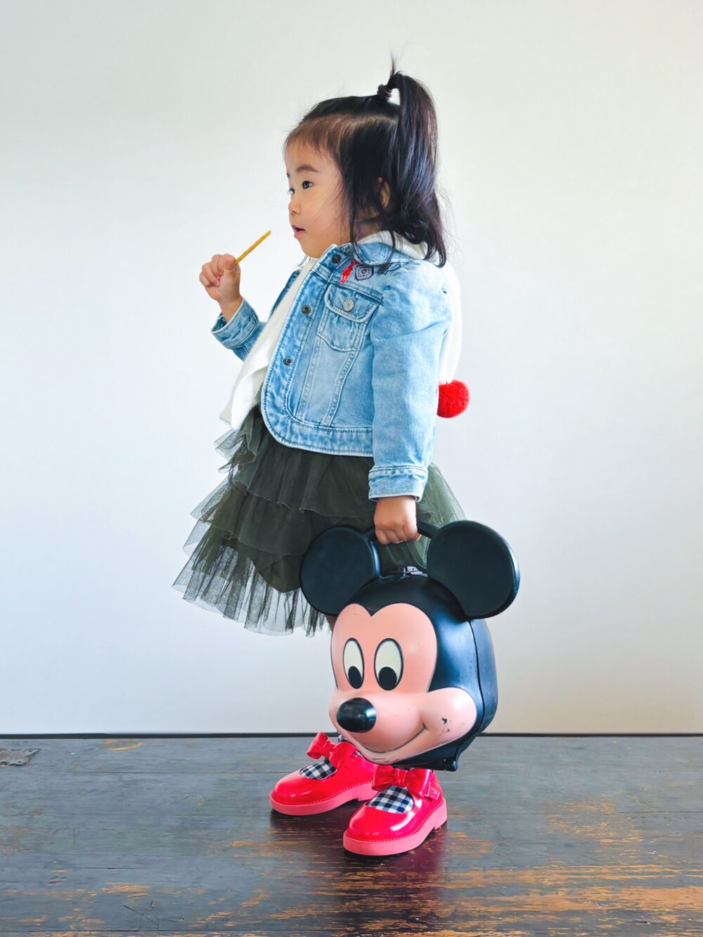 ブラック系のハンドバッグ、レッド系のドレスシューズ、ブルー系のデニムジャケットを着用したキッズの秋コーディネートの2枚目の写真