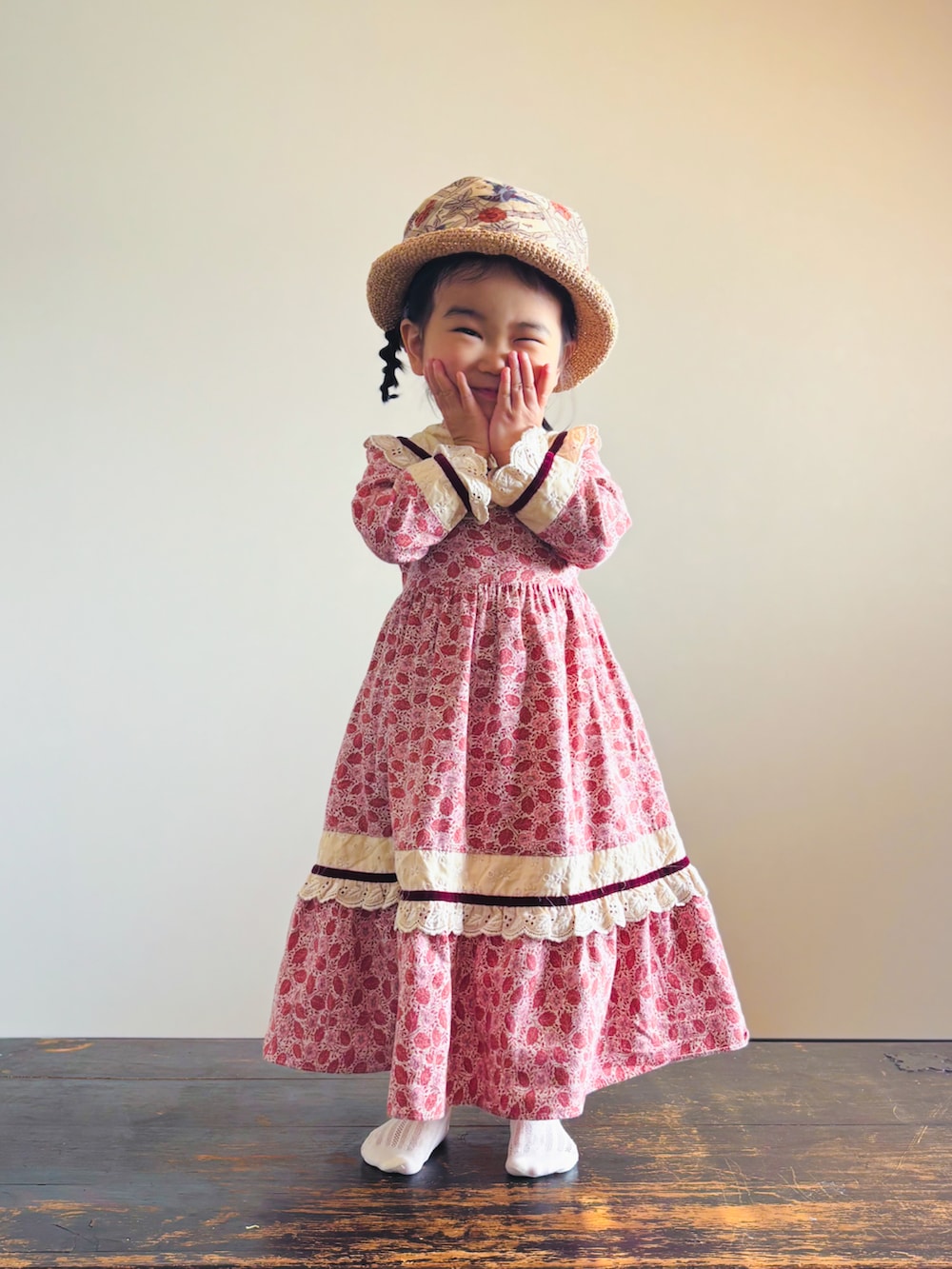 ピンク系のワンピース、ベージュ系の帽子、その他のバンダナ/スカーフを着用したキッズの春コーディネートの2枚目の写真