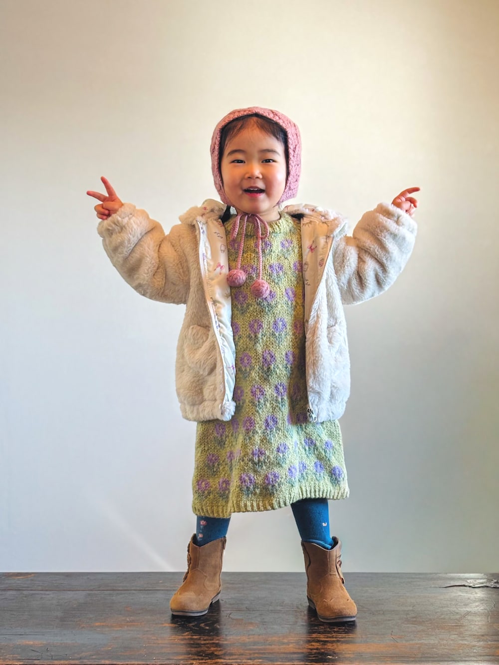 ベージュ系のブルゾン、グリーン系のワンピース、ブラウン系のブーツを着用したキッズの冬コーディネートの3枚目の写真