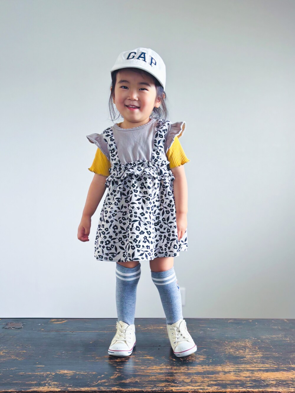 ベージュ系のワンピース、イエロー系のTシャツ/カットソー、ホワイト系のスニーカーを着用したキッズの夏コーディネートの3枚目の写真