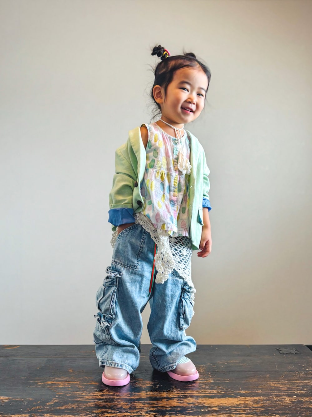 ブルー系のデニムパンツ、グリーン系のテーラードジャケット、ピンク系のワンピースを着用したキッズの秋コーディネートの3枚目の写真