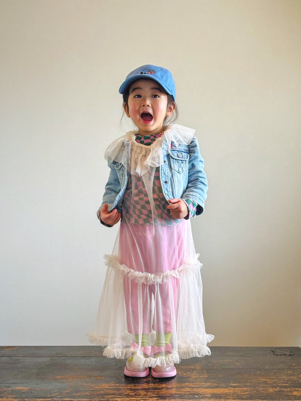ピンク系のTシャツ/カットソー、ブルー系のデニムジャケット、ホワイト系のワンピースを着用したキッズの春コーディネートの3枚目の写真