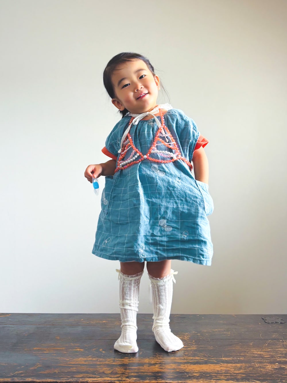 ブルー系のワンピース、オレンジ系のTシャツ/カットソー、ホワイト系のソックス/靴下を着用したキッズの夏コーディネートの3枚目の写真