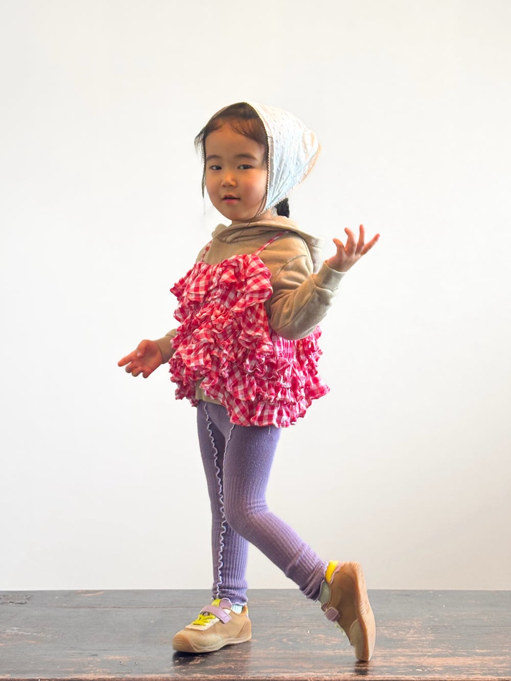 ピンク系のキャミソール、イエロー系のスニーカー、ベージュ系のパーカーを着用したキッズの春コーディネートの3枚目の写真