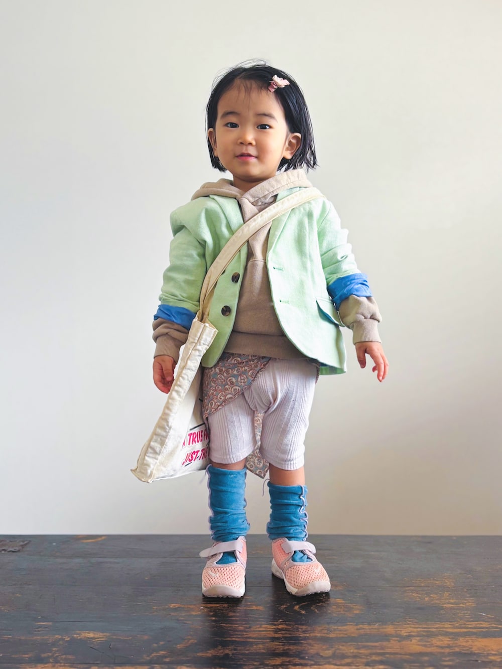 ピンク系のスニーカー、ホワイト系のトートバッグ、グリーン系のテーラードジャケットを着用したキッズの春コーディネートの2枚目の写真