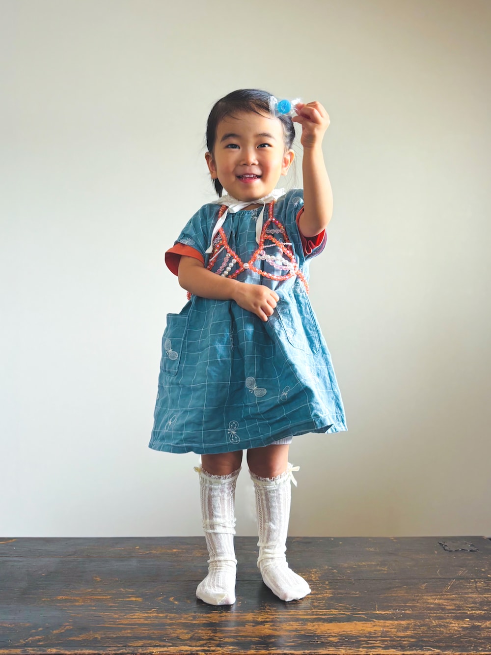 ブルー系のワンピース、オレンジ系のTシャツ/カットソー、ホワイト系のソックス/靴下を着用したキッズの夏コーディネートの2枚目の写真