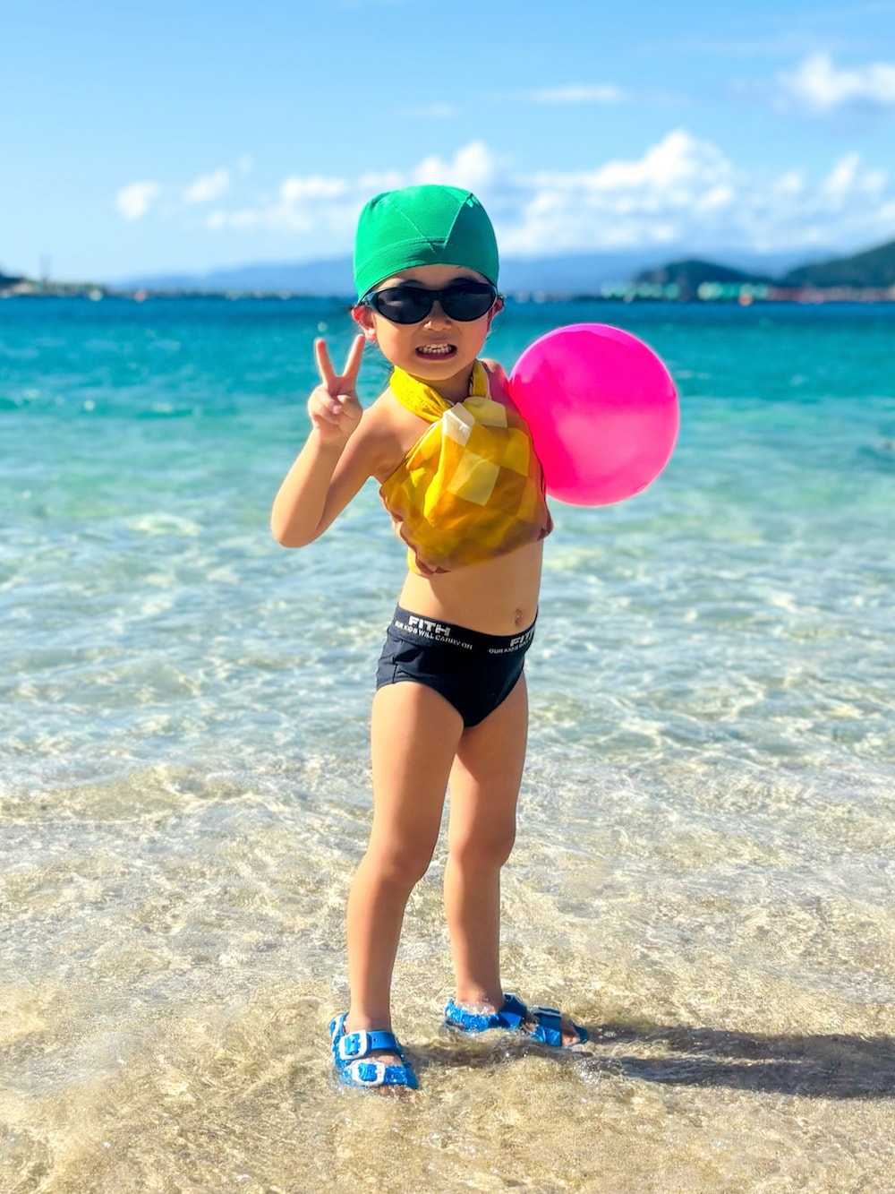 ブルー系のサンダル、ブラック系のサングラス、イエロー系のバンダナ/スカーフを着用したキッズの夏コーディネートの3枚目の写真