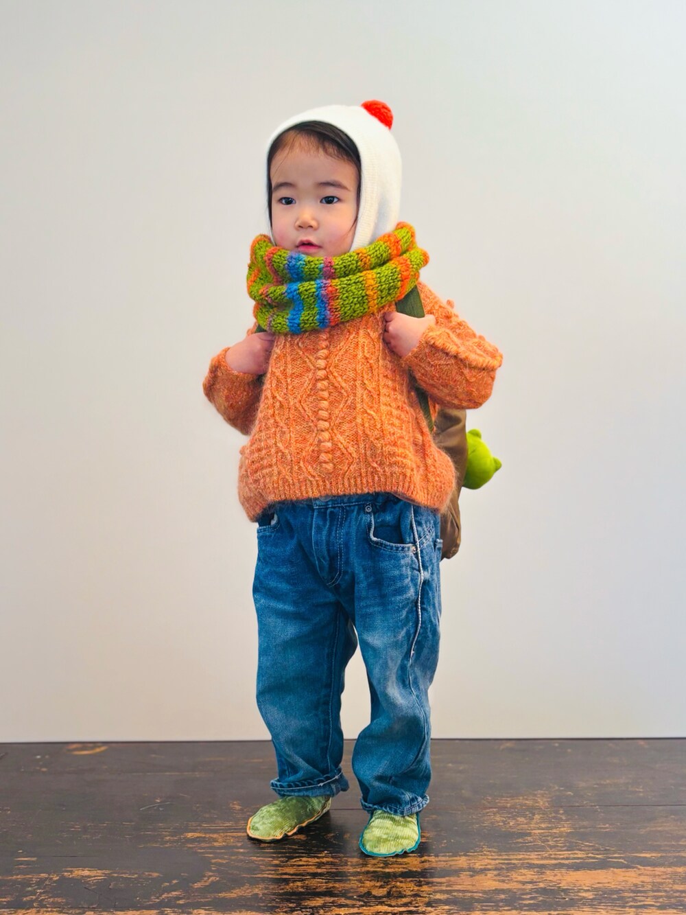 ブルー系のデニムパンツ、オレンジ系のニット/セーター、グリーン系のバックパック/リュックを着用したキッズの冬コーディネートの3枚目の写真