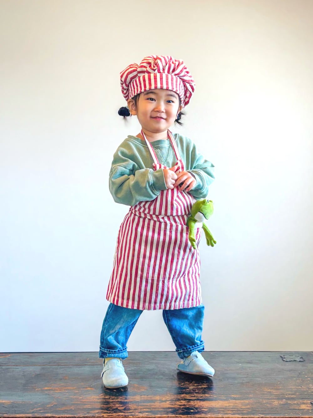 グリーン系のスウェット、ブルー系のデニムパンツ、ブルー系のサンダルを着用したキッズの秋コーディネートの3枚目の写真