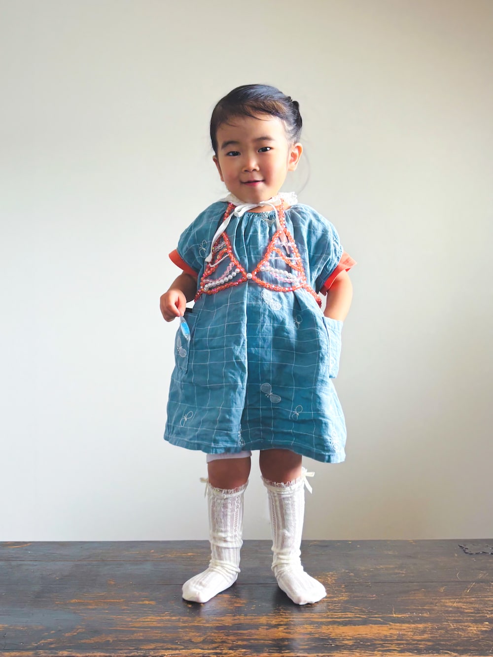 ブルー系のワンピース、オレンジ系のTシャツ/カットソー、ホワイト系のソックス/靴下を着用したキッズの夏コーディネートの4枚目の写真