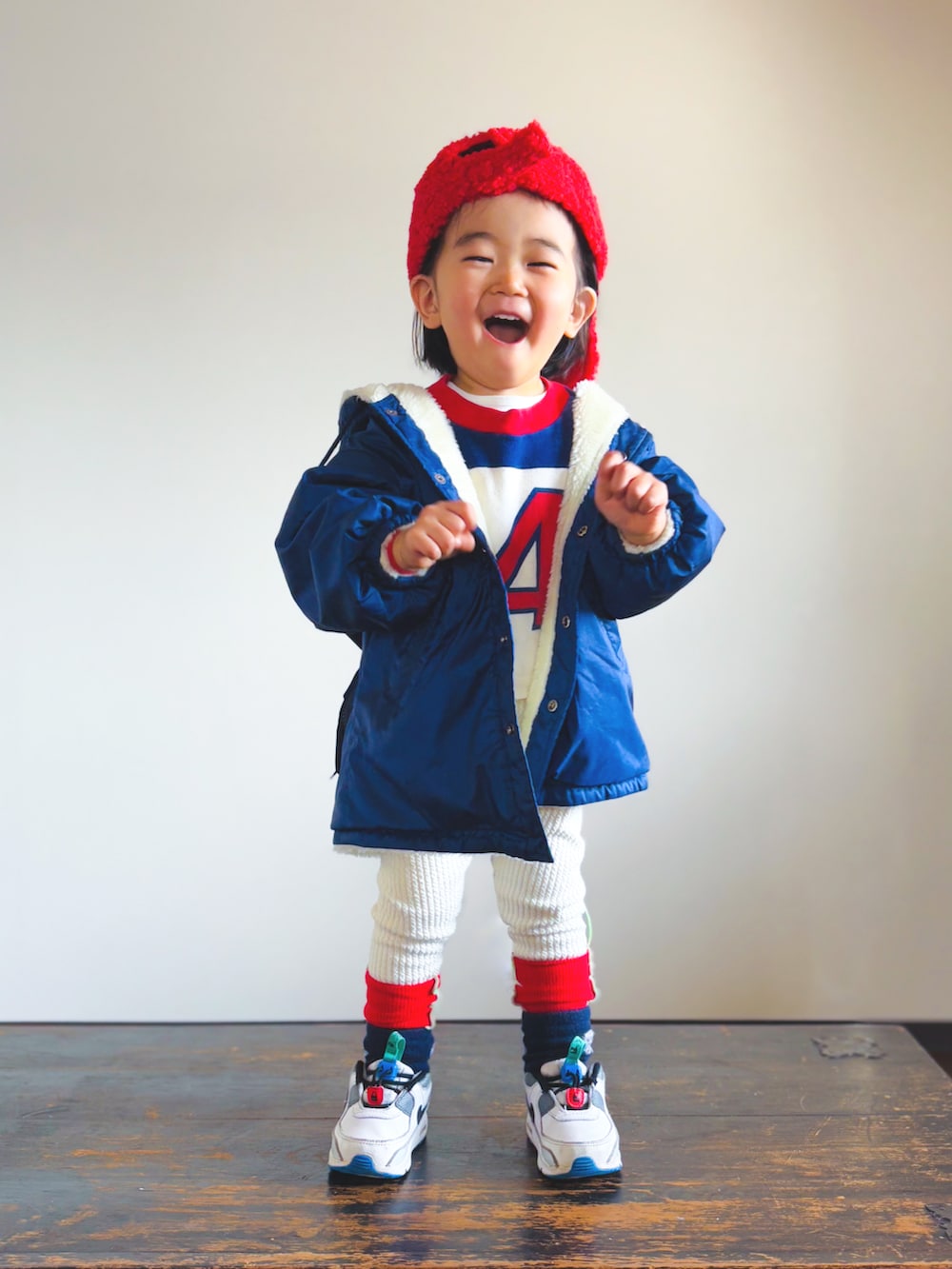 ブルー系のナイロンジャケット、ホワイト系のスニーカー、レッド系のTシャツ/カットソーを着用したキッズの冬コーディネートの2枚目の写真