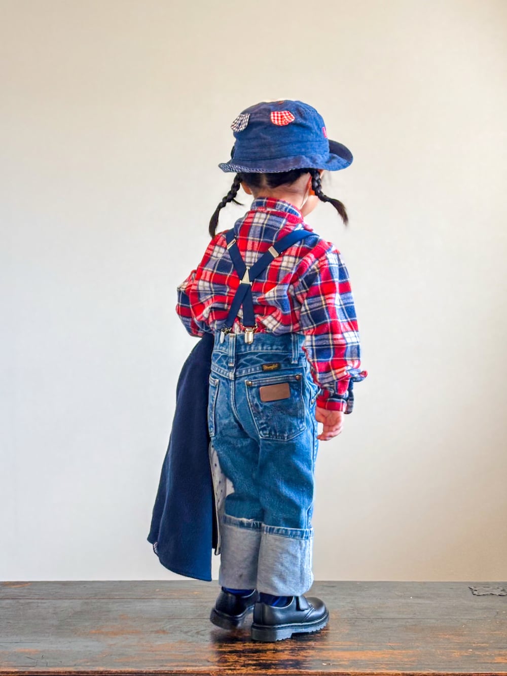 レッド系のシャツ/ブラウス、ブラック系のポンチョ、ブルー系のデニムパンツを着用したキッズの秋コーディネートの5枚目の写真