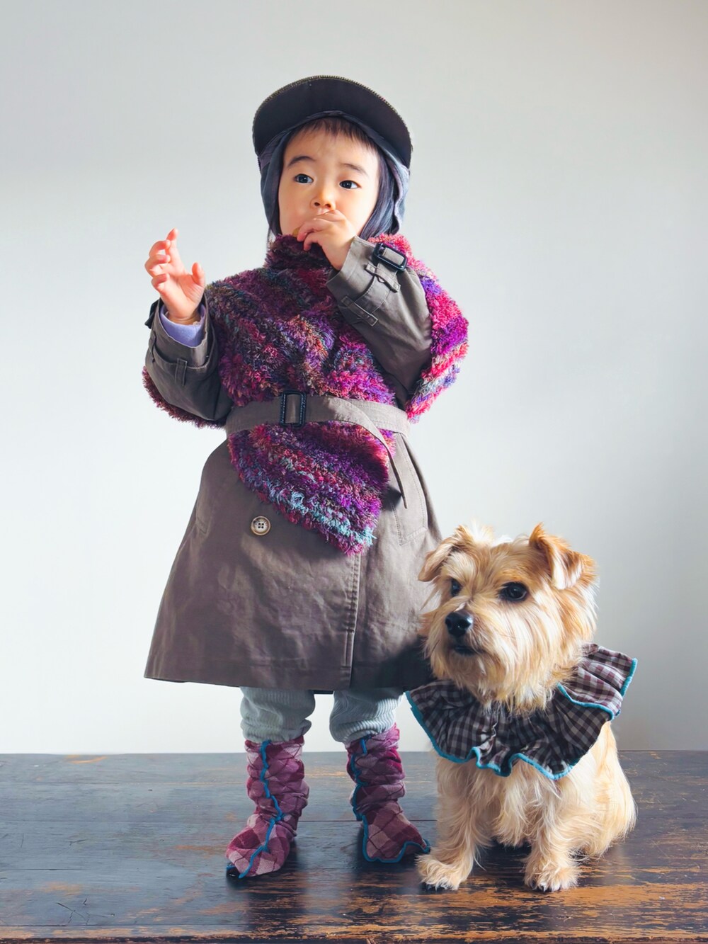 グリーン系のその他パンツ、パープル系のポンチョ、グリーン系のトレンチコートを着用したキッズの冬コーディネートの3枚目の写真