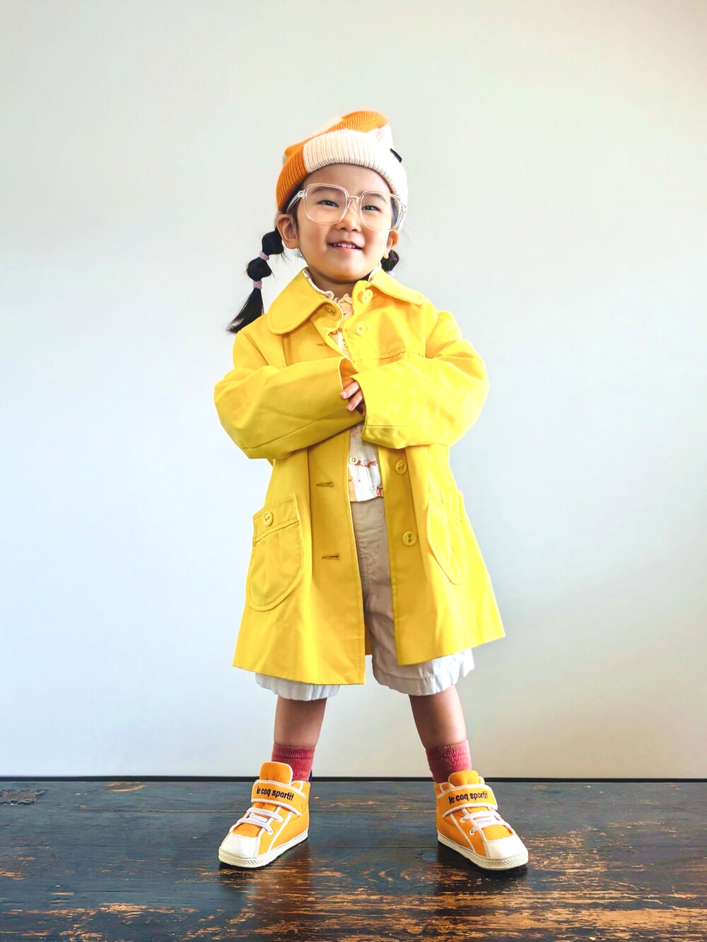 オレンジ系のスニーカー、ベージュ系のシャツ/ブラウス、イエロー系のステンカラーコートを着用したキッズの秋コーディネートの3枚目の写真
