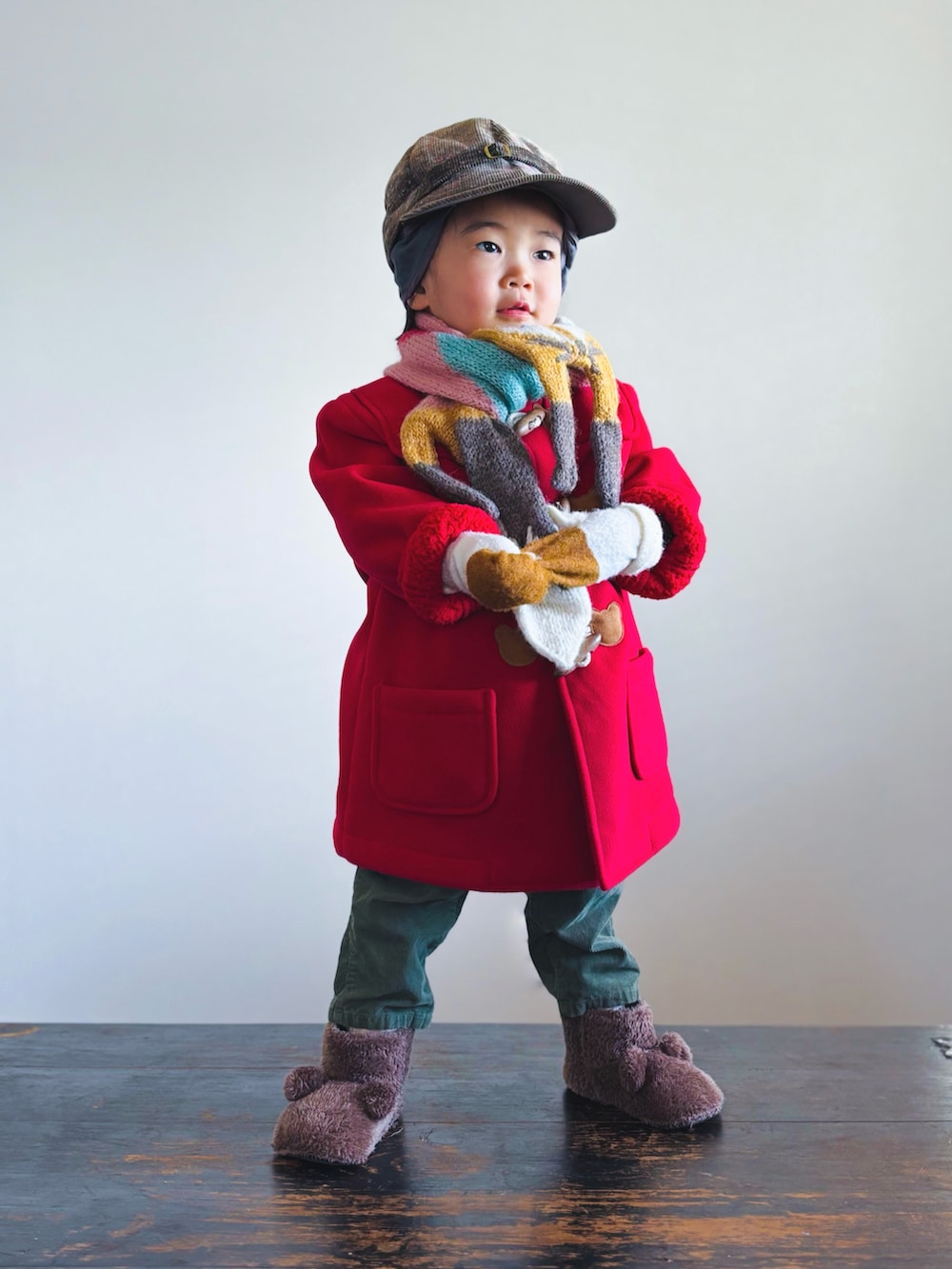 レッド系のダッフルコート、グリーン系のパンツ、ブラウン系のその他シューズを着用したキッズの冬コーディネートの2枚目の写真