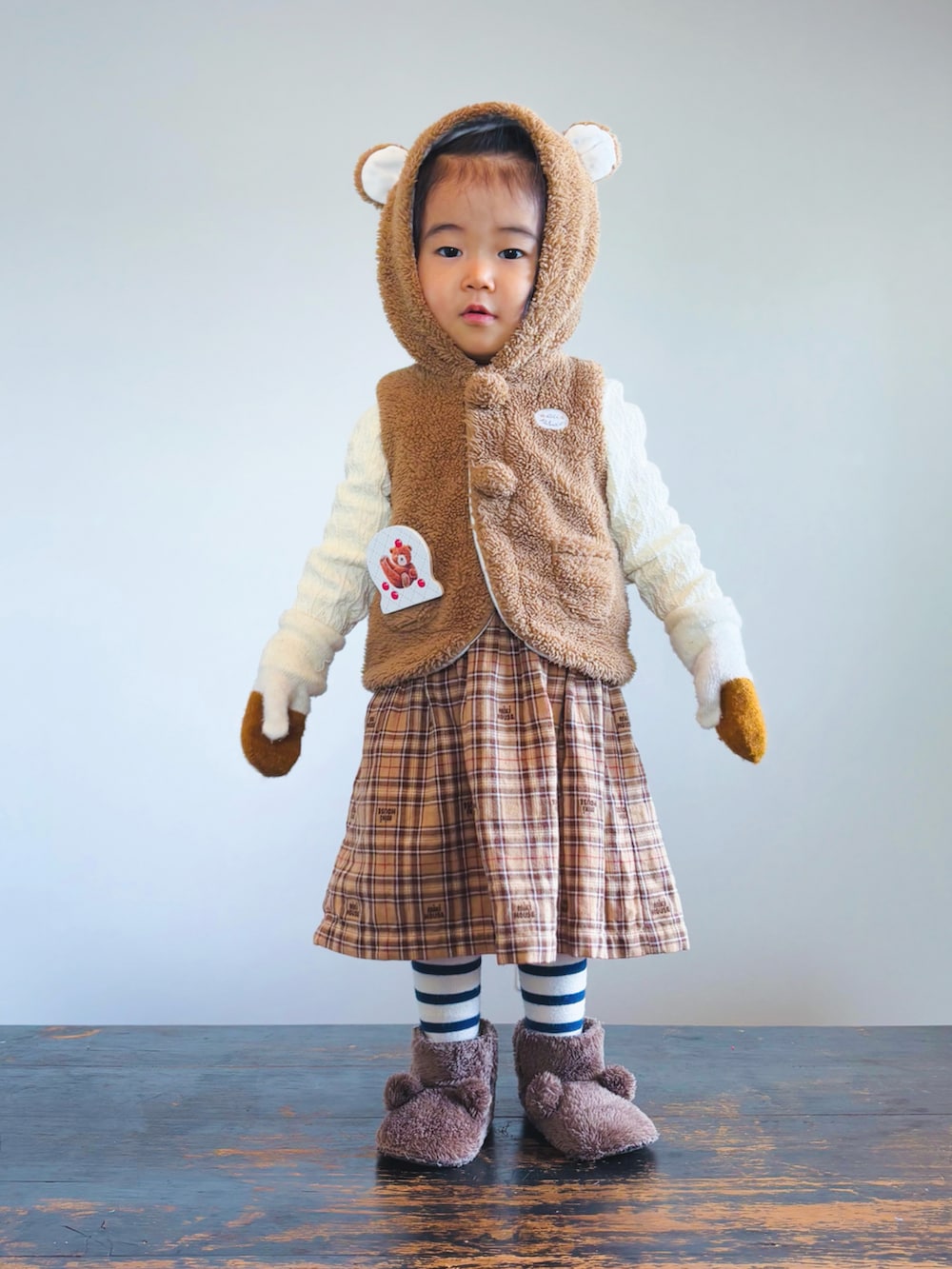 ブラウン系のベスト、ベージュ系のワンピース、ブラウン系のその他シューズを着用したキッズの冬コーディネートの2枚目の写真