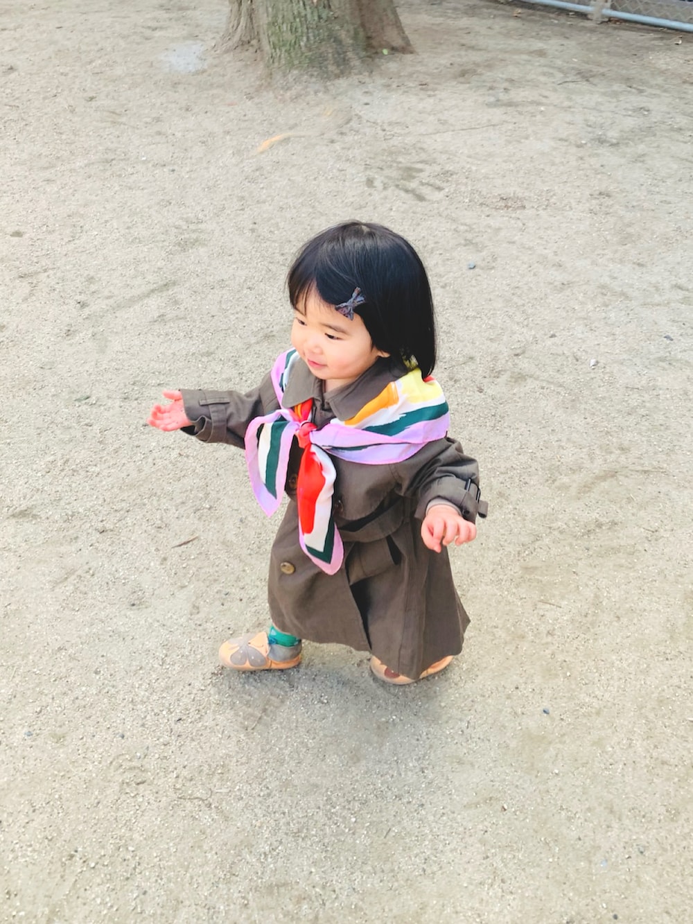 グリーン系のトレンチコート、ブラック系のその他パンツ、オレンジ系のスリッポンを着用したキッズの春コーディネートの2枚目の写真