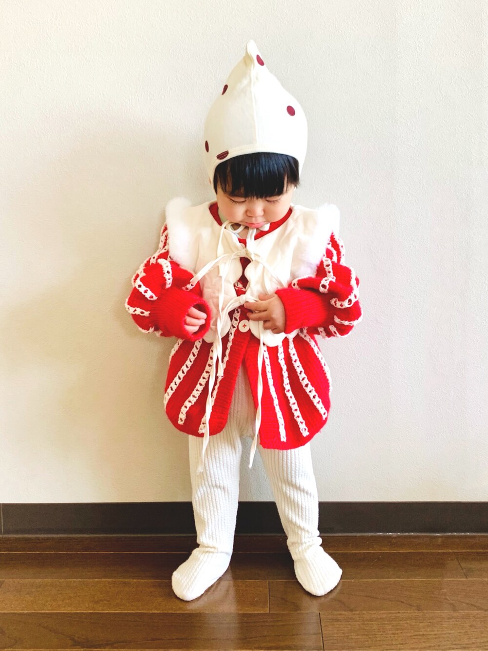 レッド系のニット/セーター、ホワイト系のベスト、ホワイト系のタイツ/ストッキングを着用したキッズの冬コーディネートの2枚目の写真