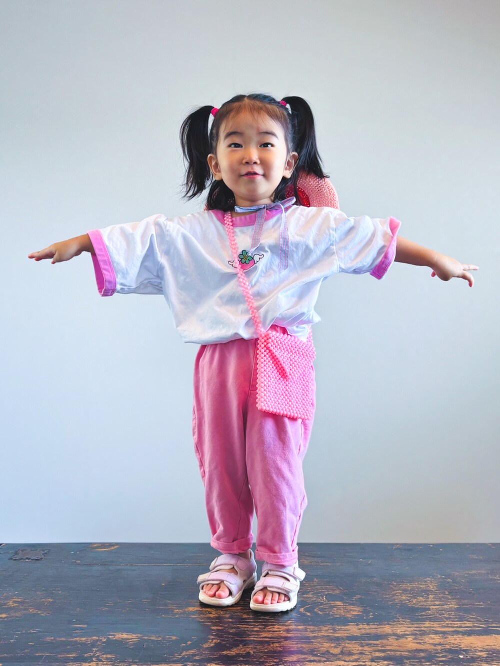 ホワイト系のTシャツ/カットソー、ピンク系のスウェットパンツ、ピンク系のショルダーバッグを着用したキッズの夏コーディネートの2枚目の写真