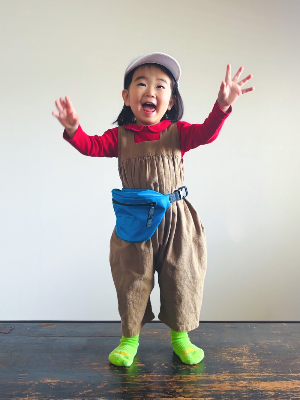 ブルー系のボディバッグ/ウエストポーチ、ベージュ系のつなぎ/オールインワン、ホワイト系のキャップを着用したキッズの春コーディネートの2枚目の写真