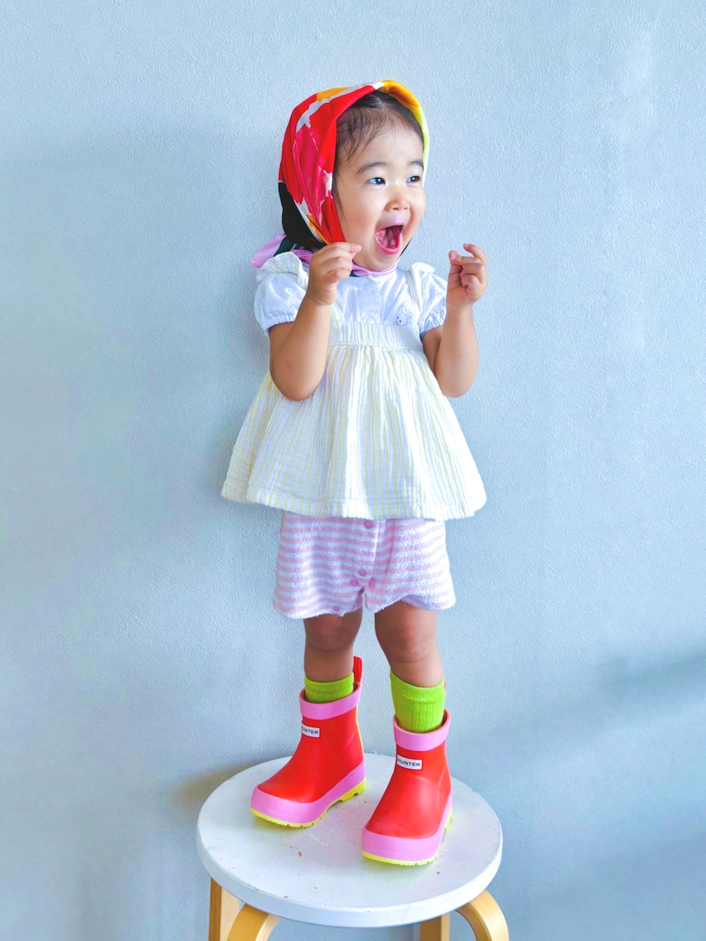 オレンジ系のレインシューズ、グリーン系のソックス/靴下、ピンク系のロンパースを着用したキッズの夏コーディネートの2枚目の写真