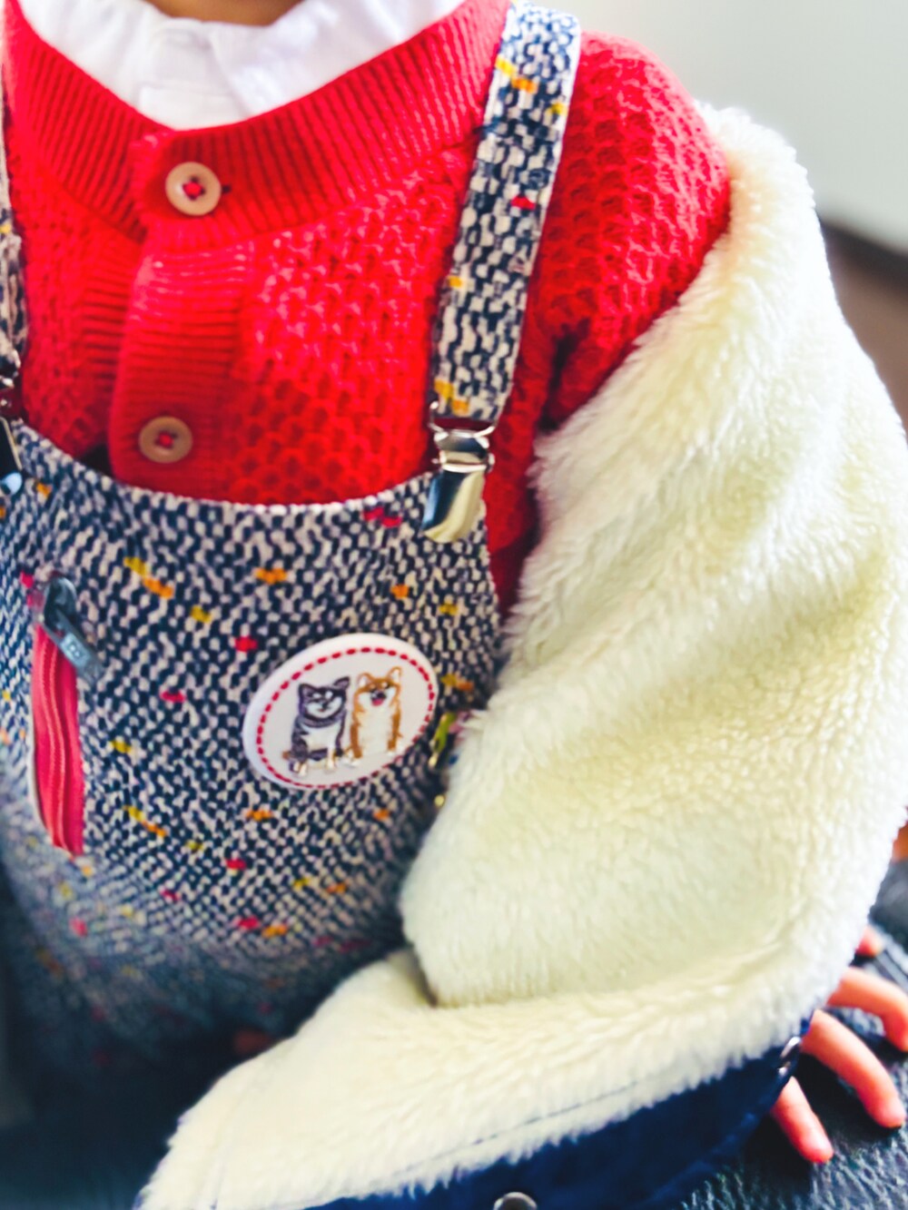 ブルー系のナイロンジャケット、レッド系のカーディガン/ボレロ、ホワイト系のシャツ/ブラウスを着用したキッズの冬コーディネートの3枚目の写真