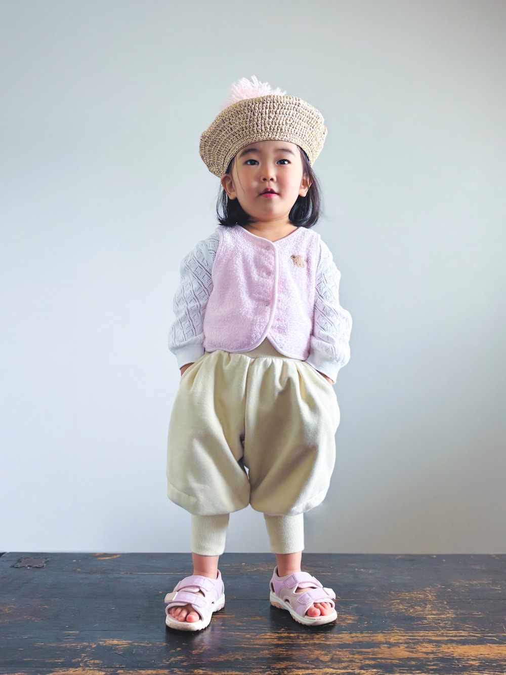 ピンク系のベスト、ホワイト系のカーディガン/ボレロ、ベージュ系のパンツを着用したキッズの春コーディネートの2枚目の写真