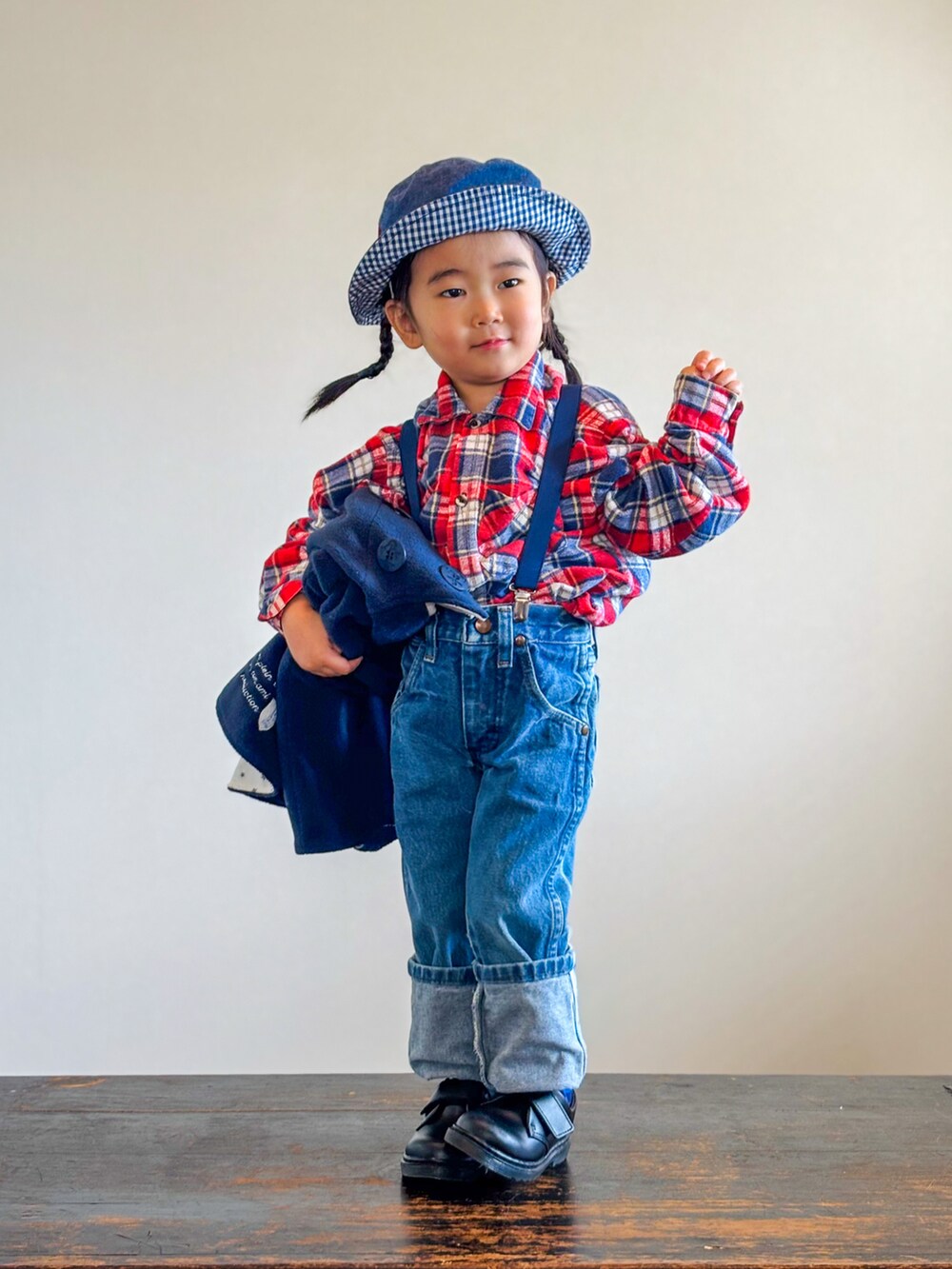 レッド系のシャツ/ブラウス、ブラック系のポンチョ、ブルー系のデニムパンツを着用したキッズの秋コーディネートの2枚目の写真