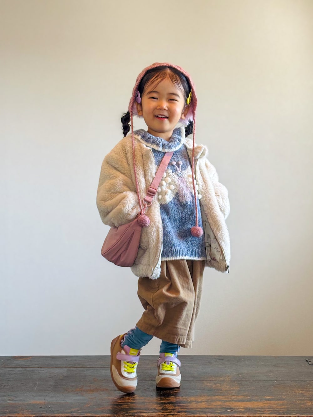 ベージュ系のブルゾン、ベージュ系のつなぎ/オールインワン、イエロー系のスニーカーを着用したキッズの冬コーディネートの2枚目の写真